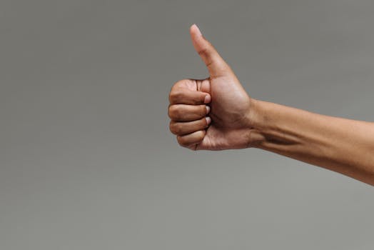pexels-photo-9486675-9486675 A close-up image of a hand making a thumbs up gesture against a neutral background.